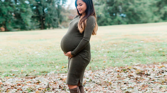 happy pregnant woman wearing a dress on fall day