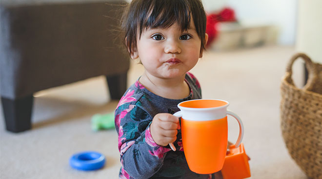 toddler child holding orange sip cup