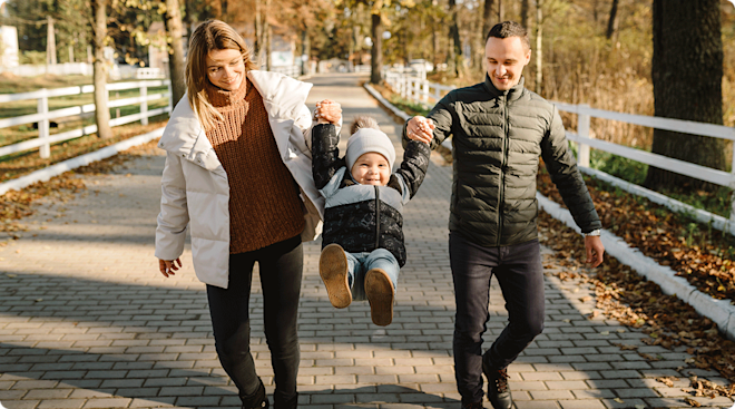 mom and dad playing with baby outside during november