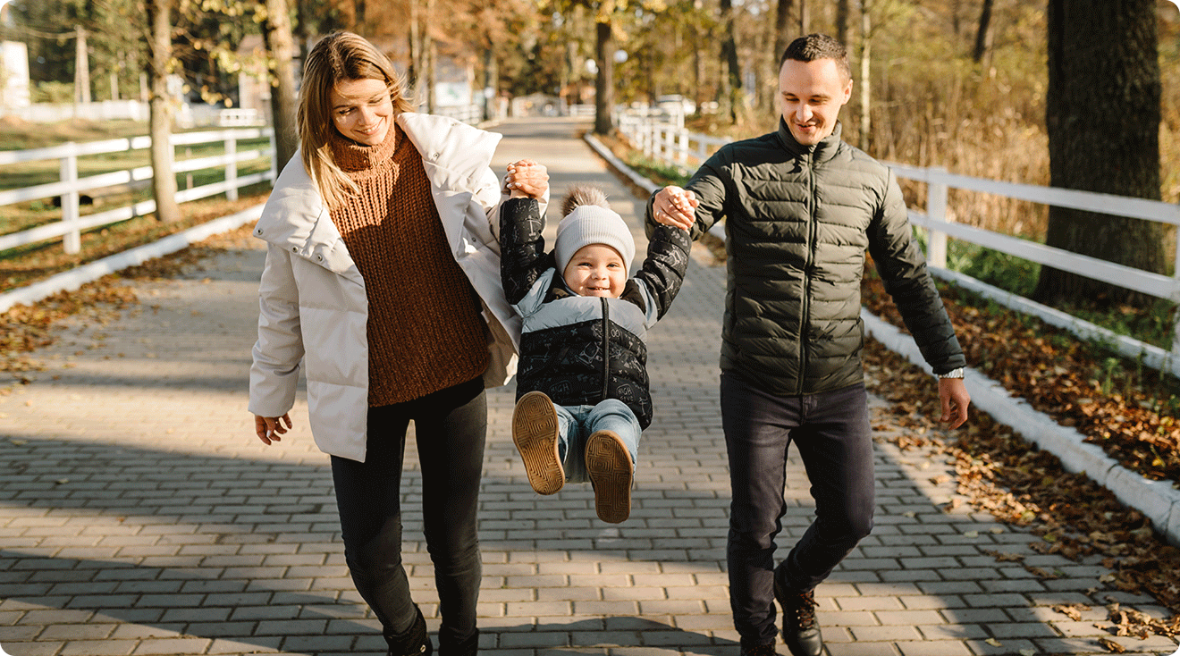 mom and dad playing with baby outside during november