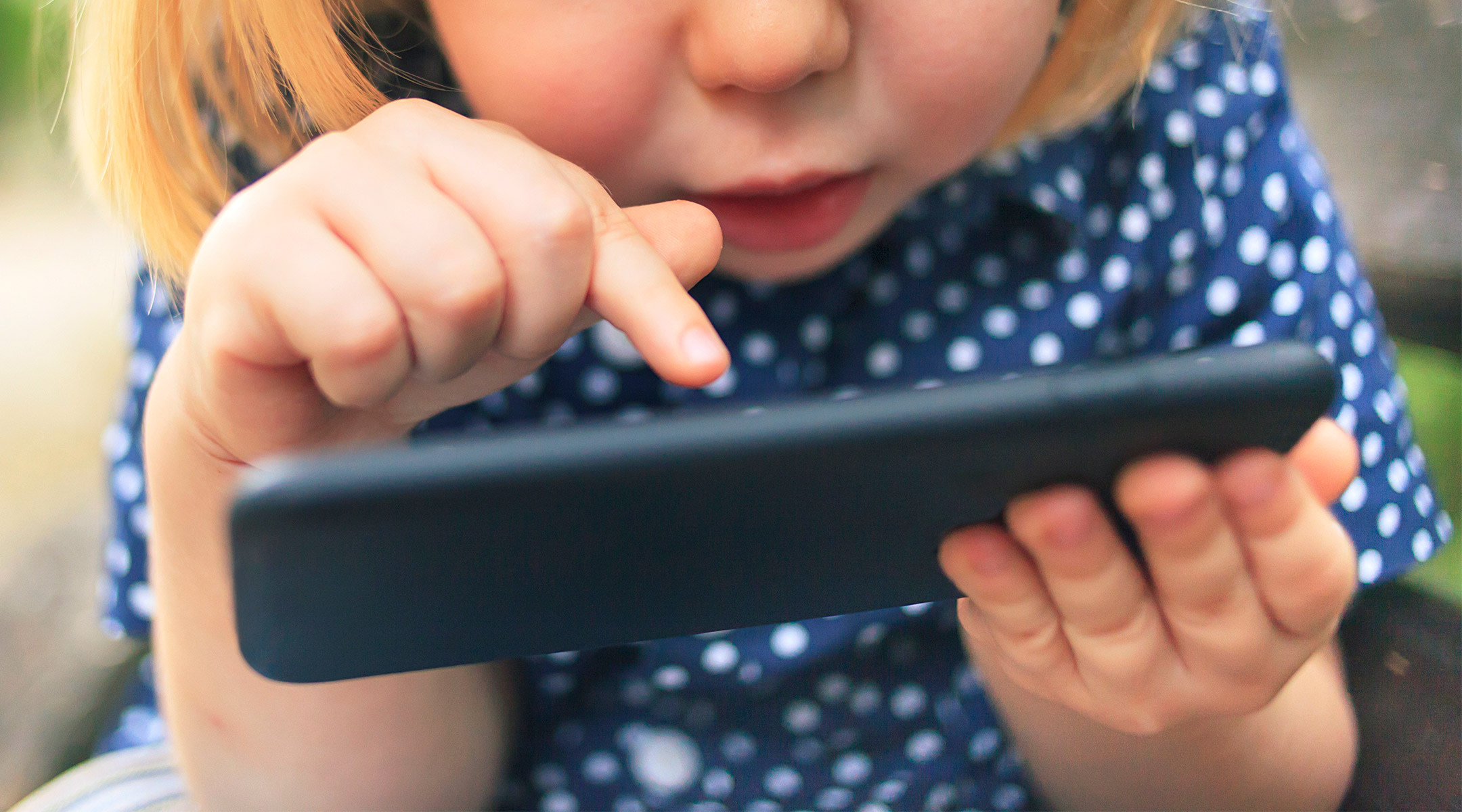 toddler girl intently uses a mobile phone 