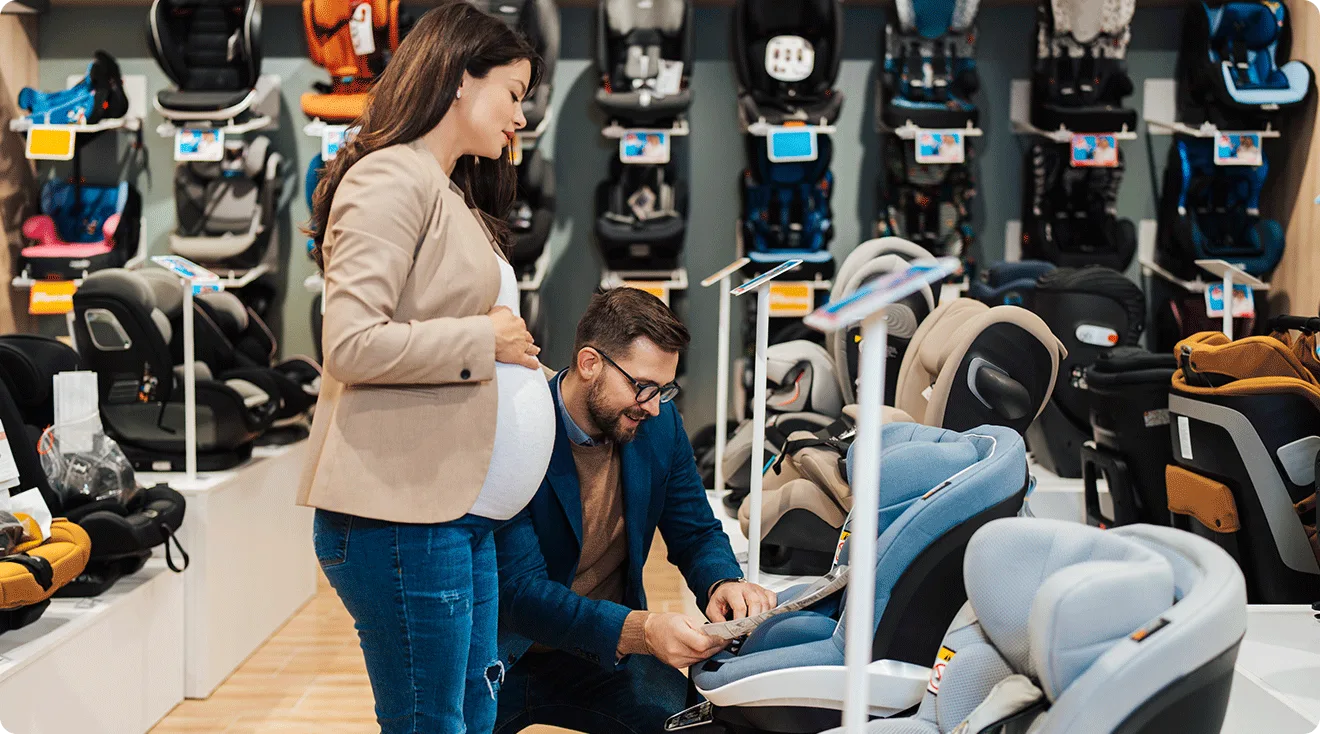 pregnant couple shopping for baby car seats in store