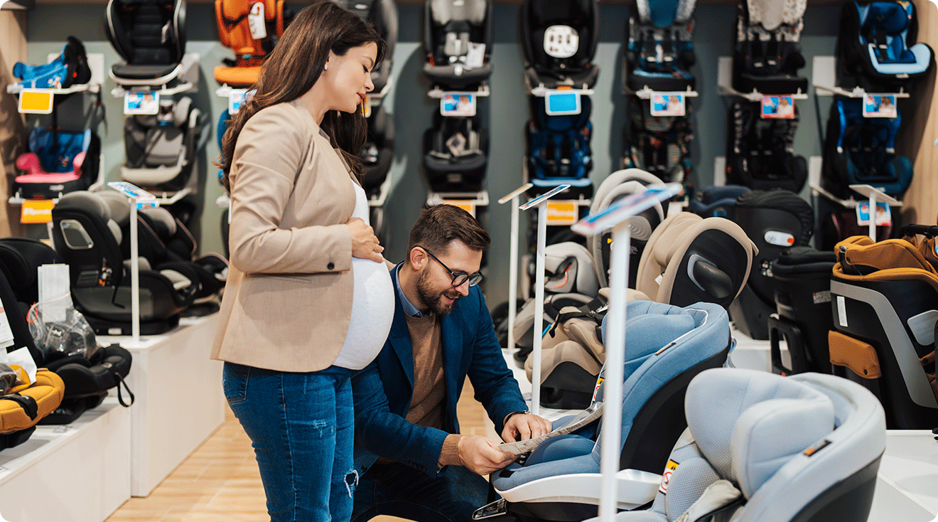 pregnant couple shopping for baby car seats in store