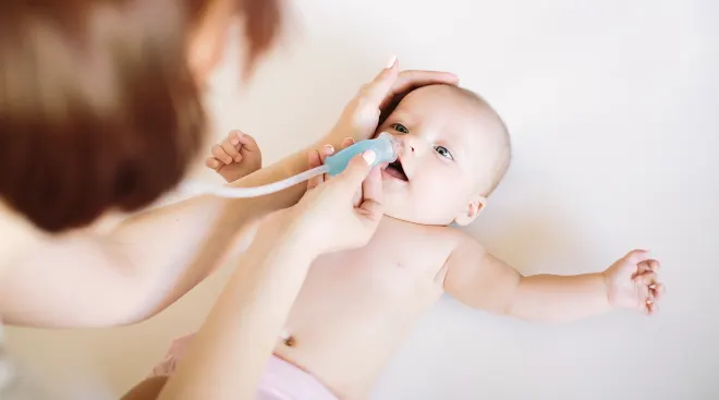 mother using oral nasal aspirator on baby