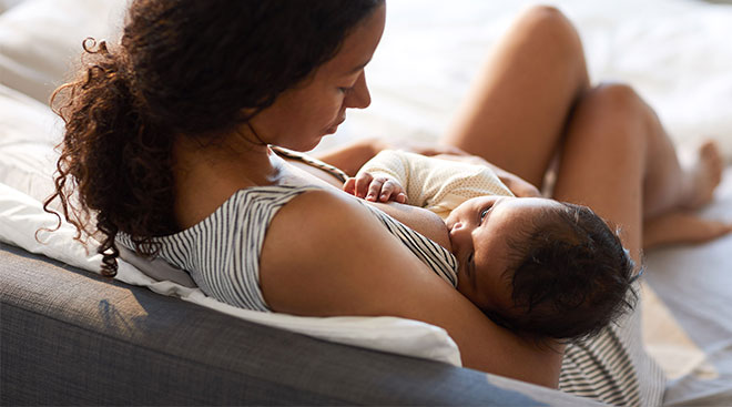 mom breastfeeding her baby at home on the couch