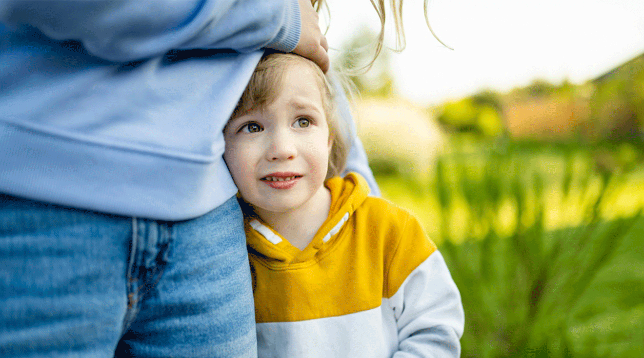 nervous toddler holding onto mom before school drop off