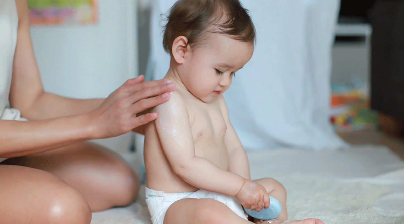 mom putting lotion on baby