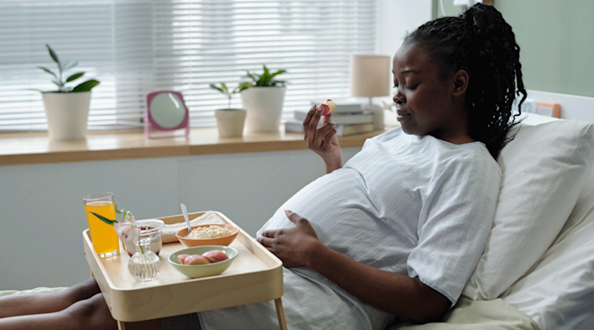 pregnant woman eating in hospital bed before labor