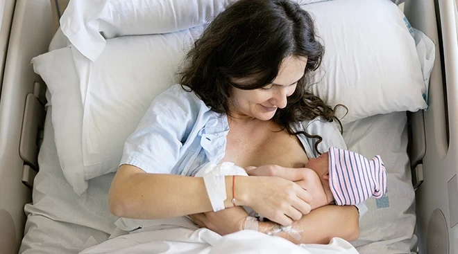mother breastfeeding newborn baby in hospital bed after giving birth