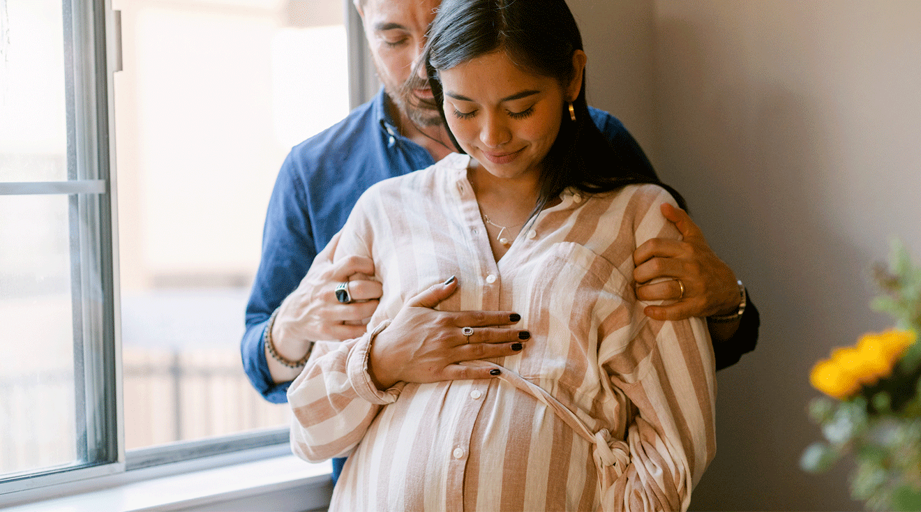 pregnant couple embracing at home