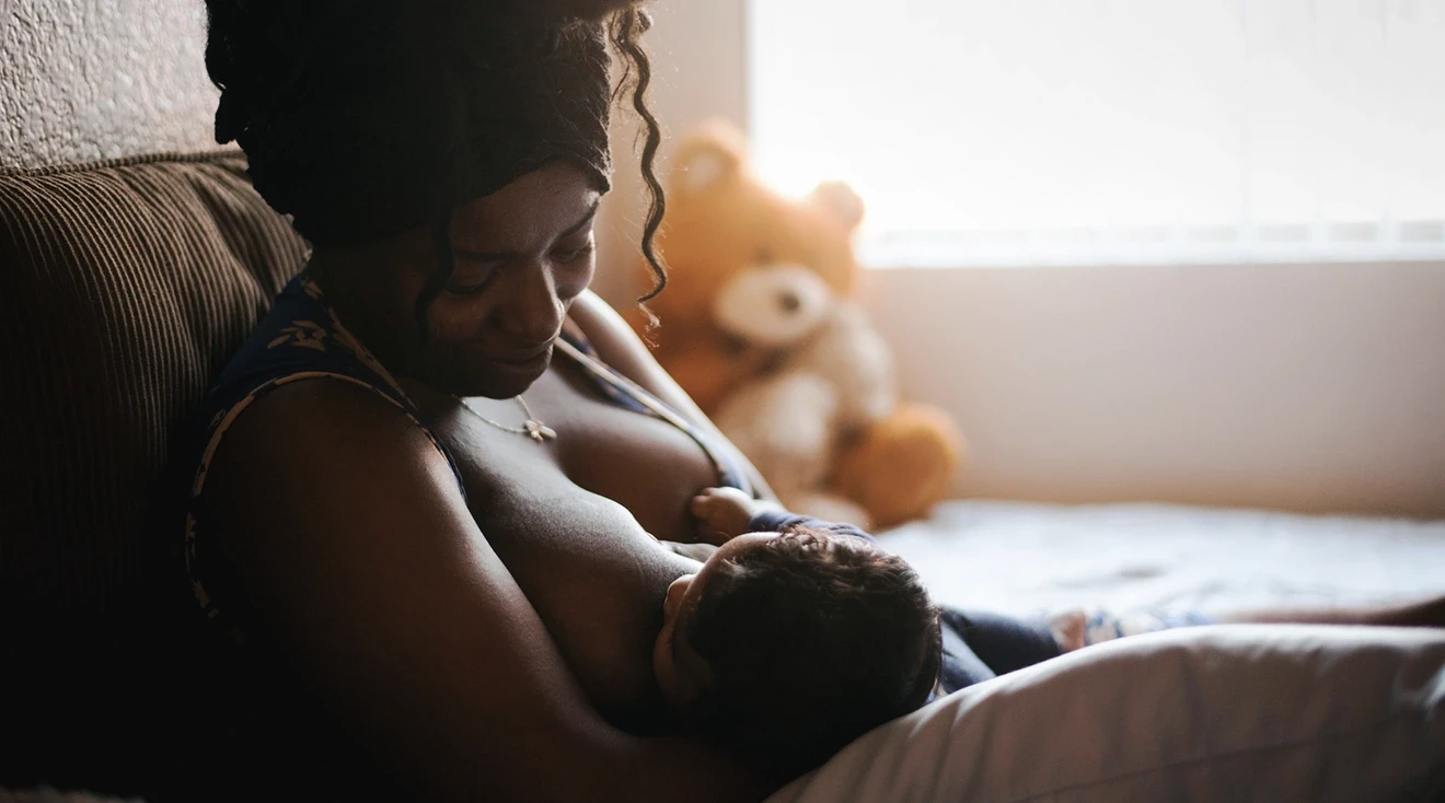 black mother breastfeeding baby at home