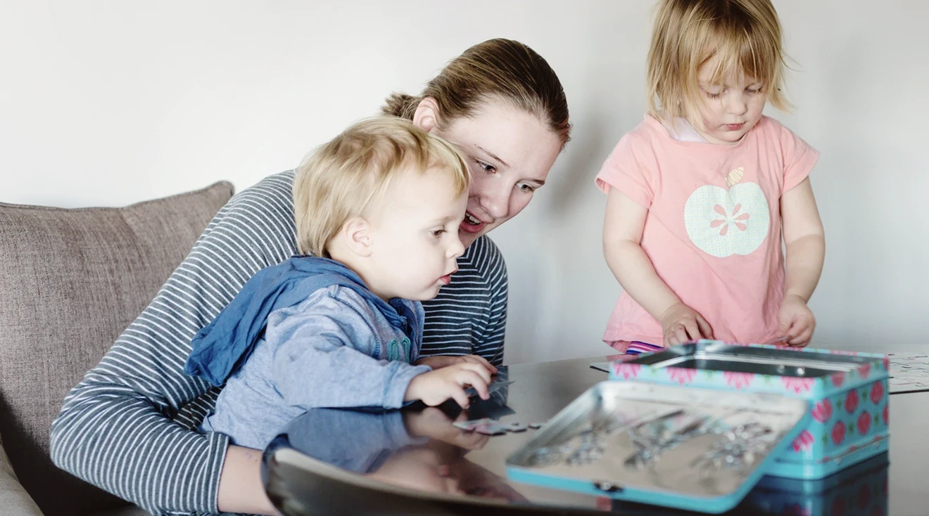 babysitter playing with two children at home