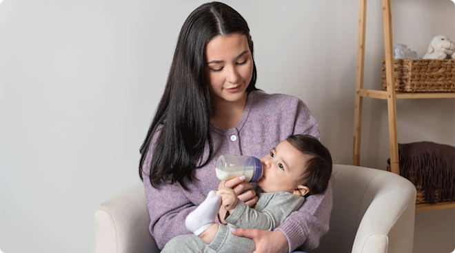 A mother feeding her baby with a Lansinoh baby bottle.
