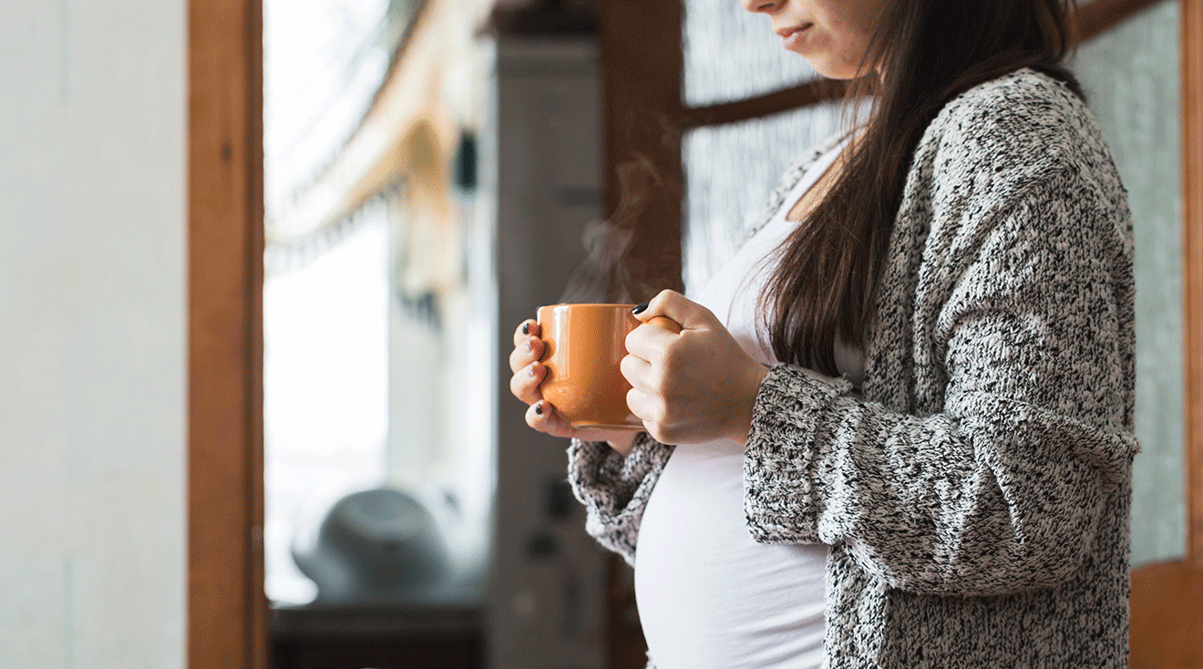 pregnant woman holding a hot cup of tea