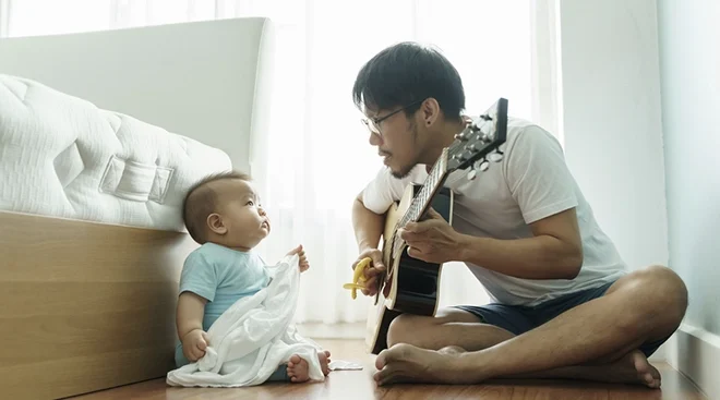 father singing and playing guitar for baby