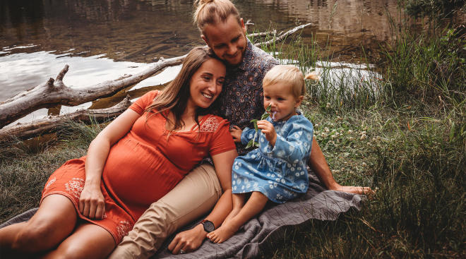 pregnant mom and her partner with their toddler toddler in scenic outdoors