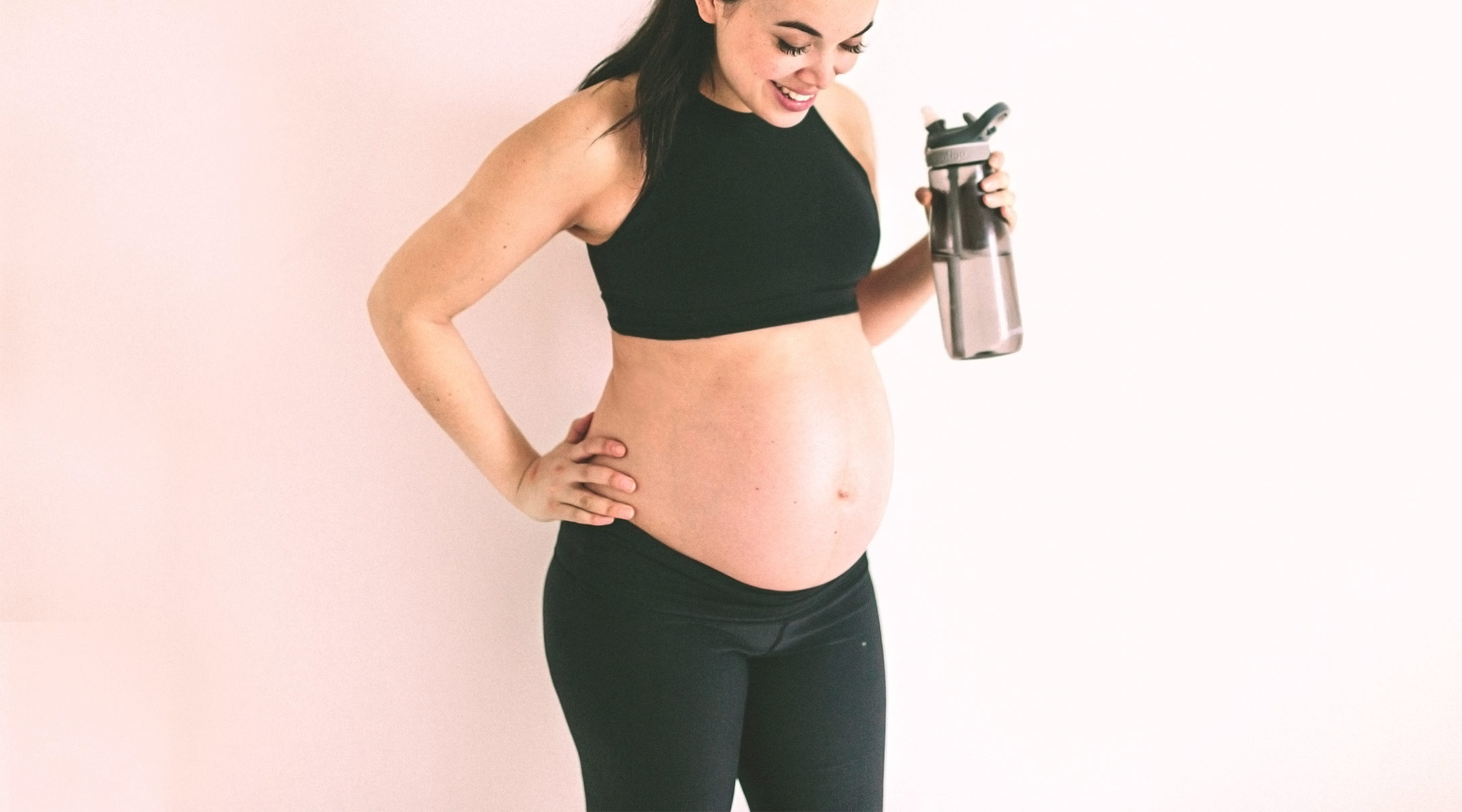 pregnant woman in workout gear carrying water bottle