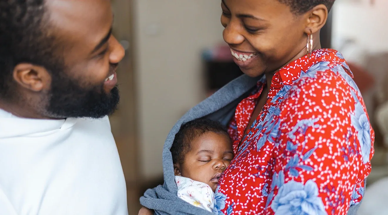 parents smiling with newborn baby at home