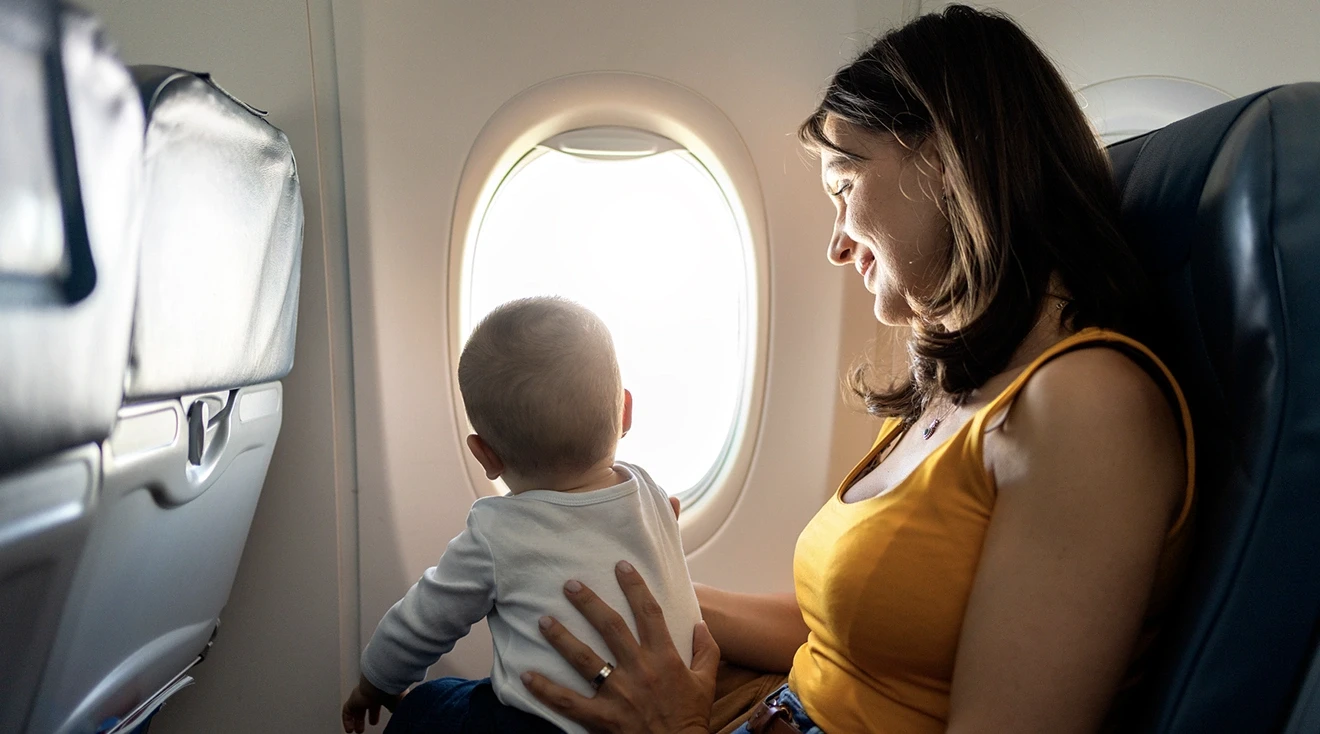 mother holding baby while sitting on airplane