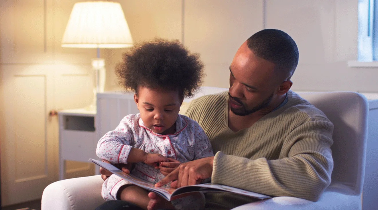 father reading book at bedtime to toddler daughter