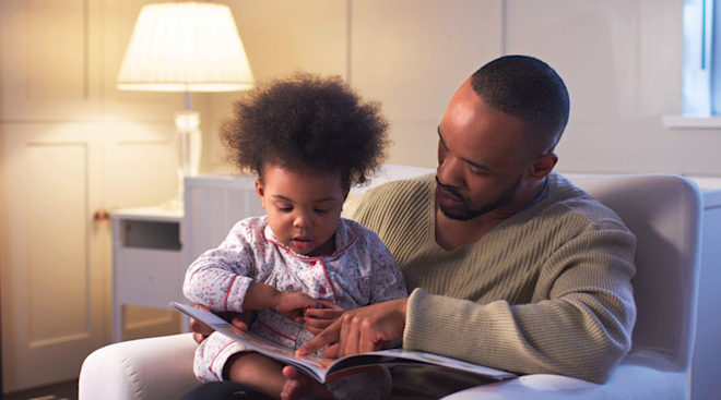 father reading book at bedtime to toddler daughter