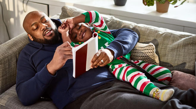 dad reading book to his son during the holidays