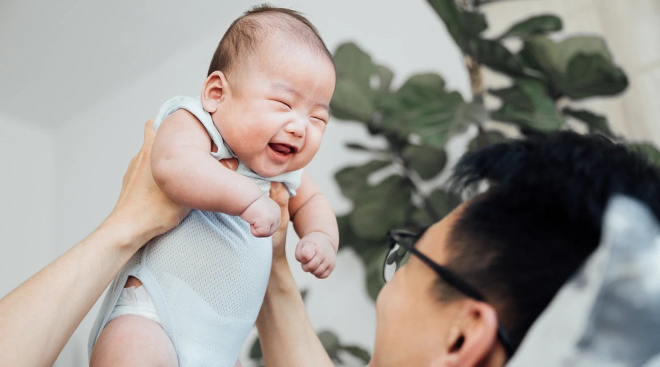 father holding up laughing baby