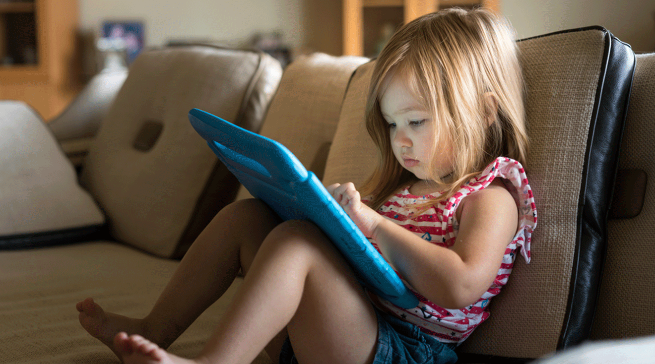 toddler sitting on couch at home with ipad