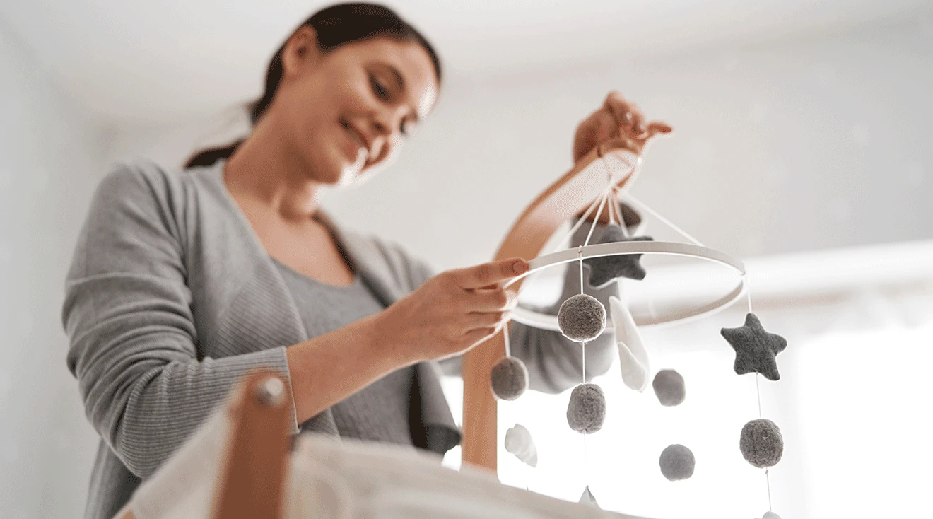 pregnant woman holding baby mobile decorating baby nursery