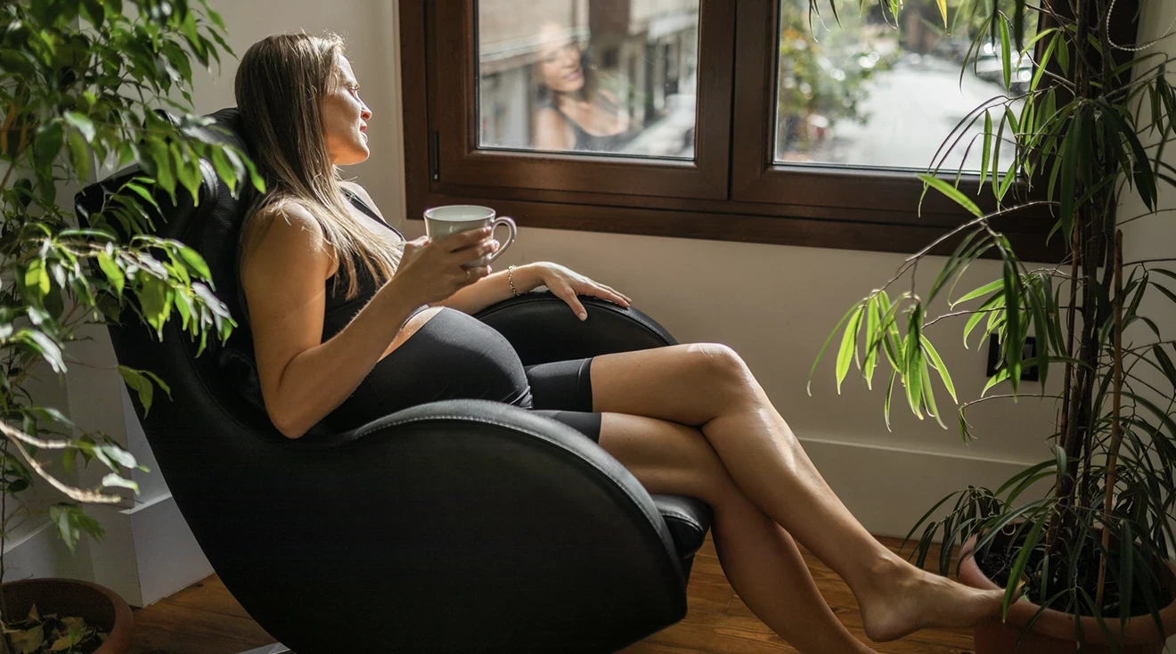 pregnant woman sitting in chair at home while looking out the window