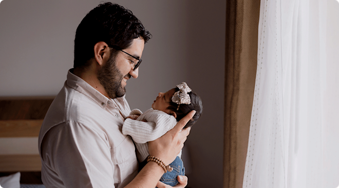 dad holding newborn baby at home