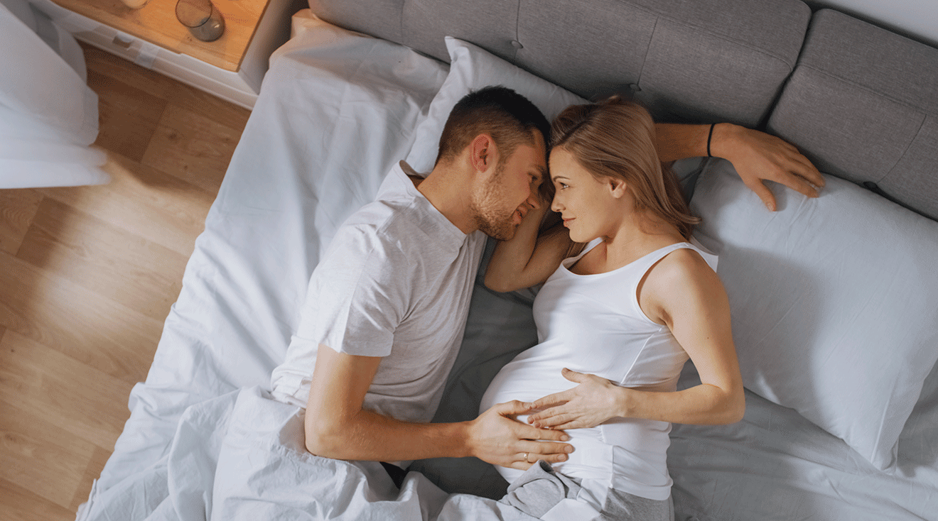 pregnant couple embracing in bed