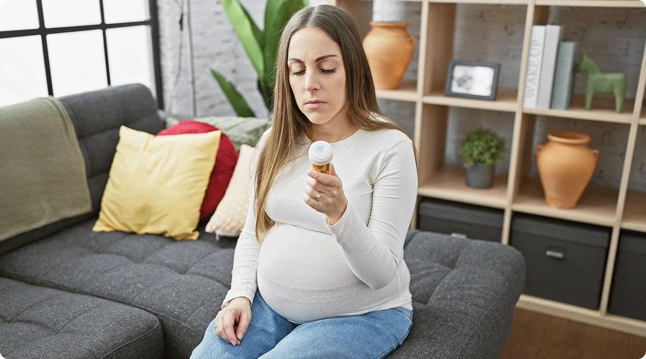 pregnant woman looking at prescription pill bottle