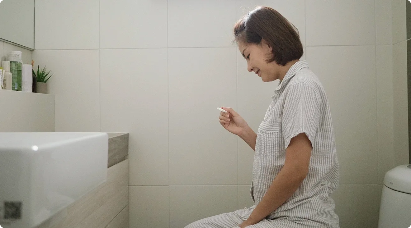 woman taking ovulation test on toilet at home