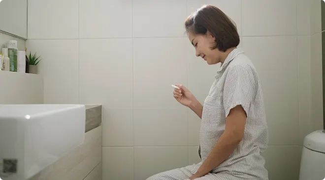 woman taking ovulation test on toilet at home