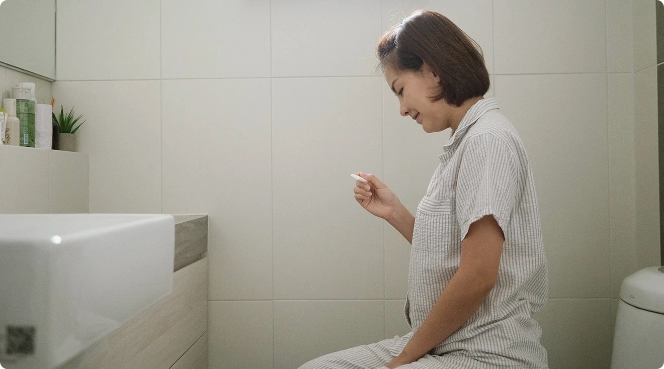 woman taking ovulation test on toilet at home