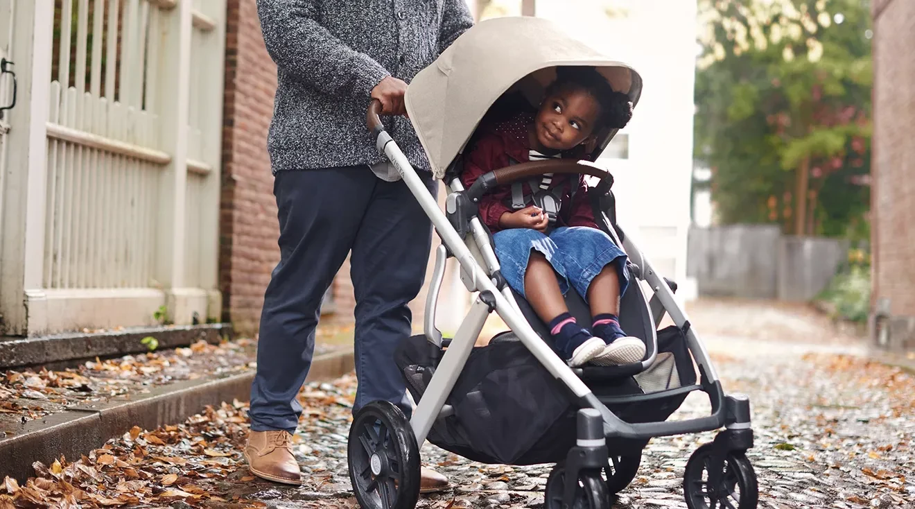 Parent pushing baby stroller outside 