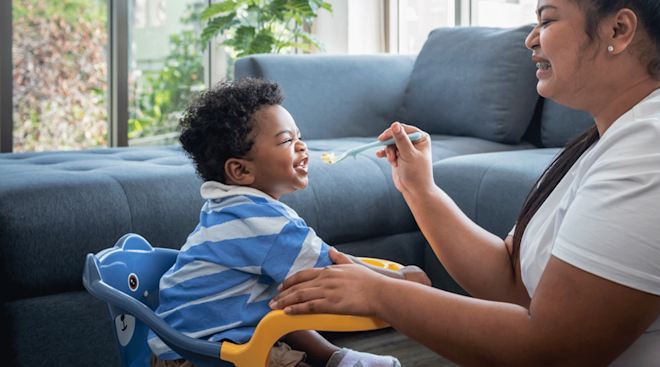 mom feeding baby food in chair at home