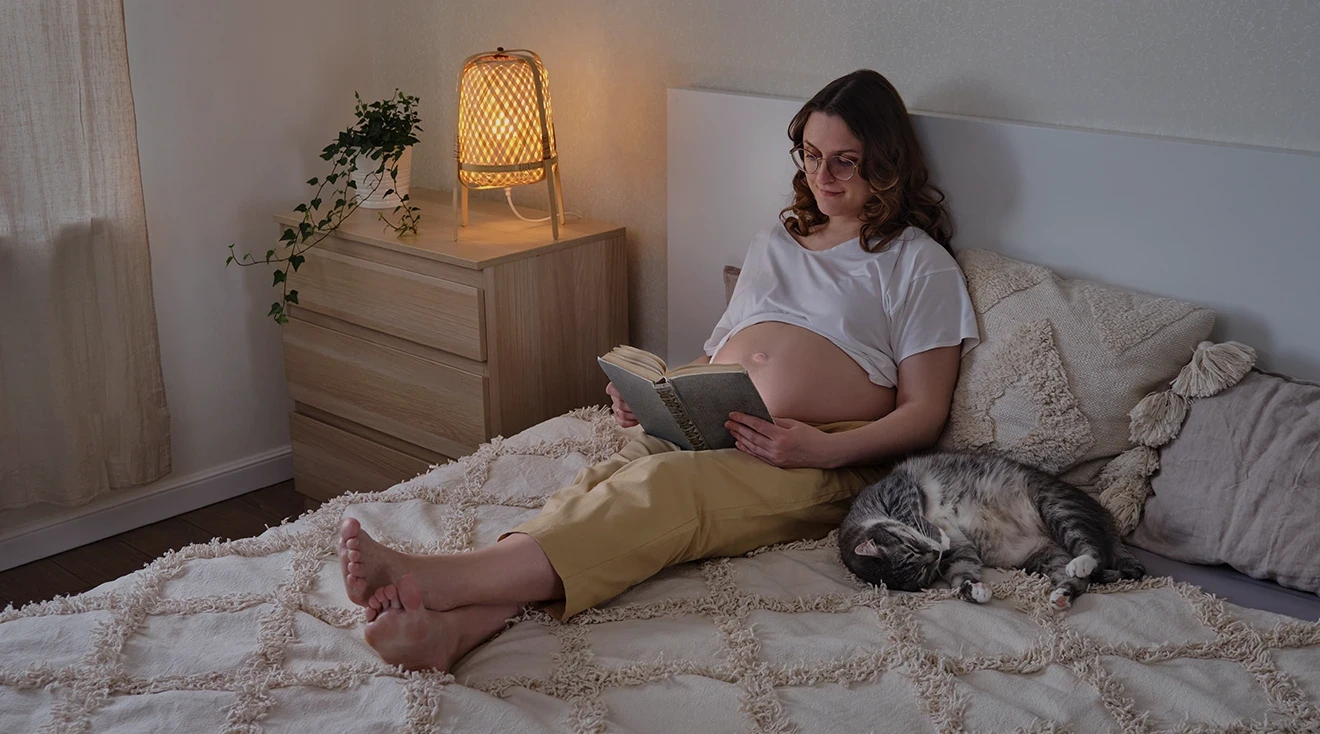 pregnant woman sitting in bed at night reading a book
