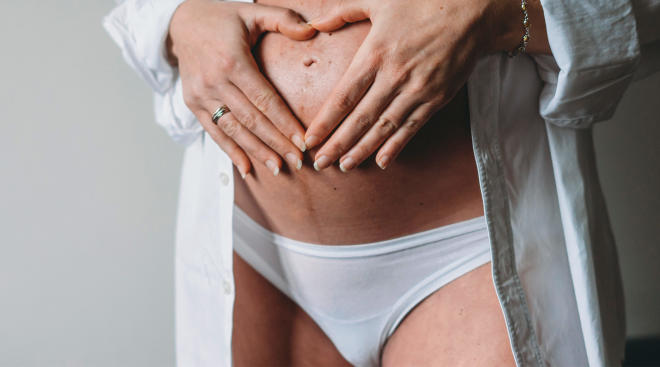 pregnant woman in her underwear with hands on her belly