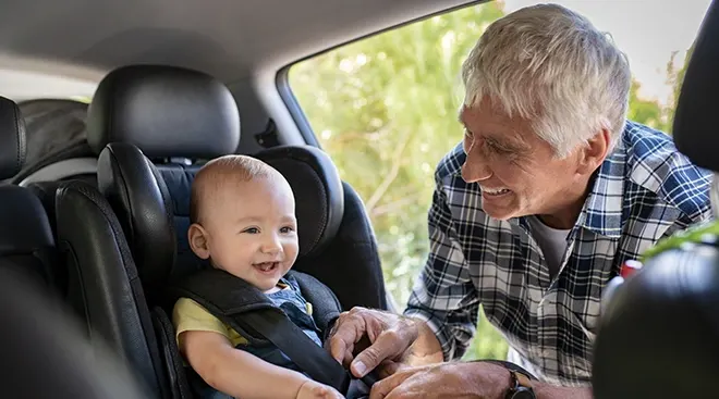 grandfather buckling baby into car seat
