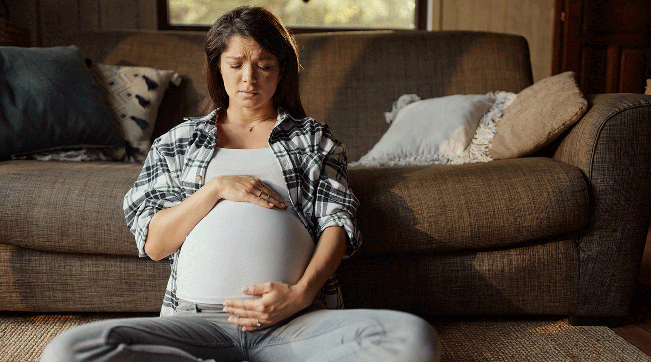 worried pregnant woman sitting at home