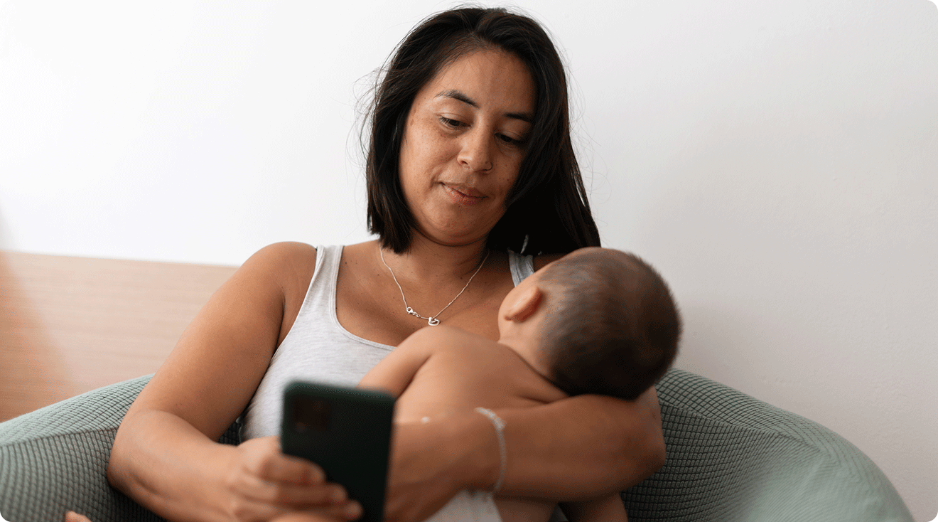mom holding baby while looking at phone
