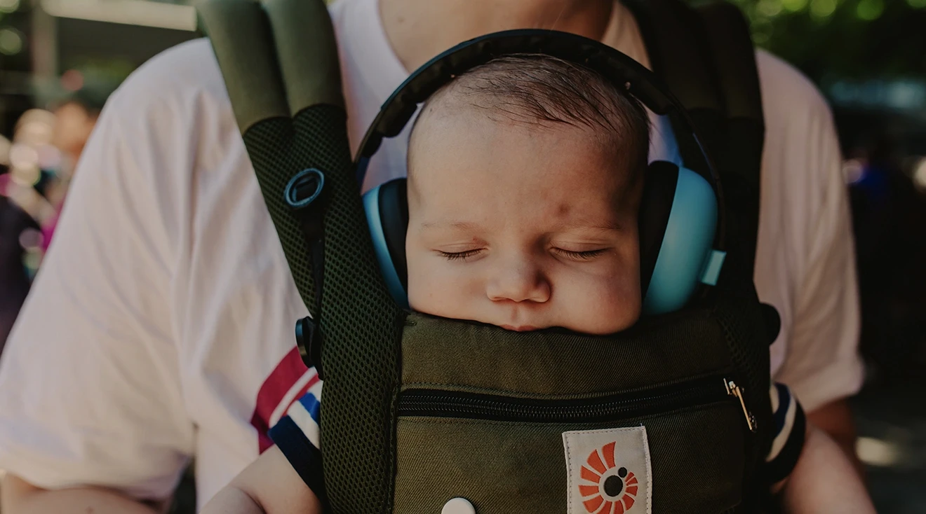 baby wearing noise cancelling headphones while asleep in baby carrier
