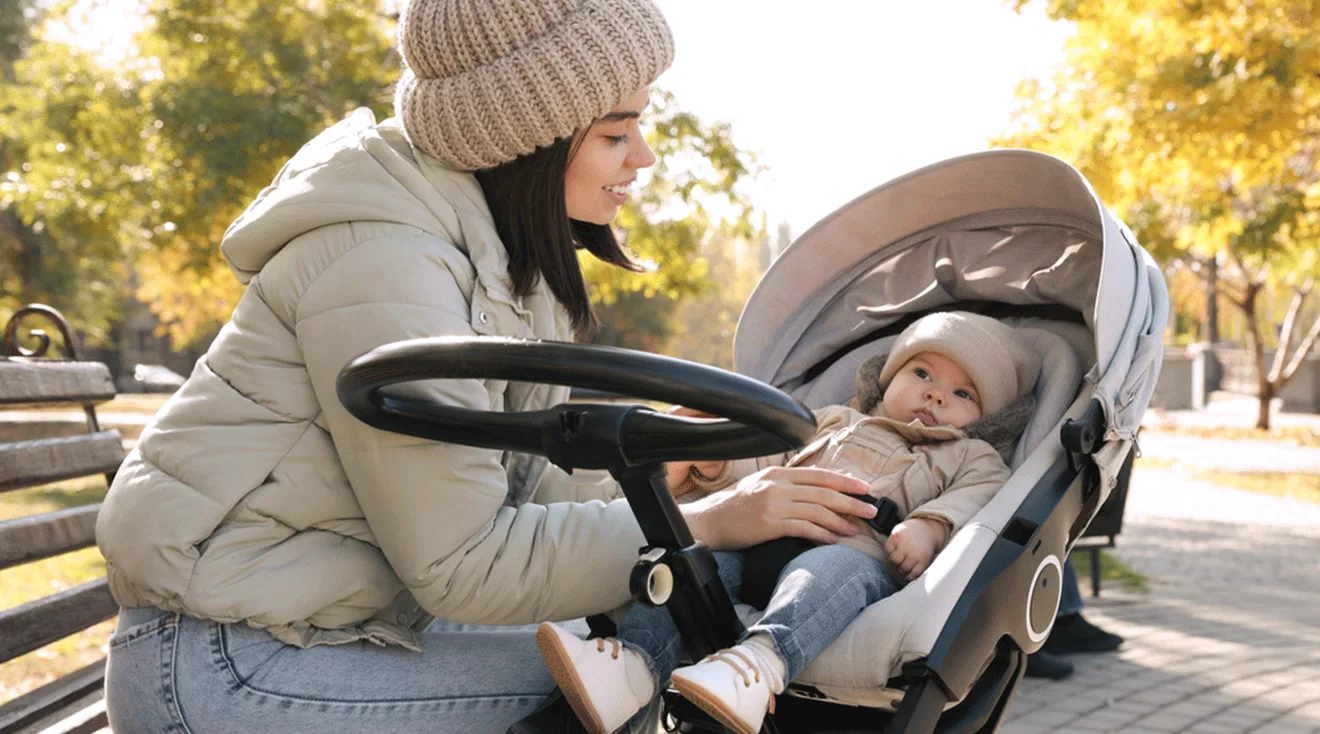 mom with baby in stroller outside during autumn