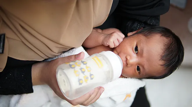 mother feeding baby a bottle