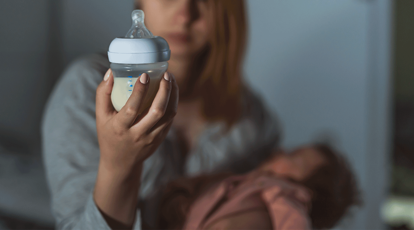 mom holding baby bottle at night