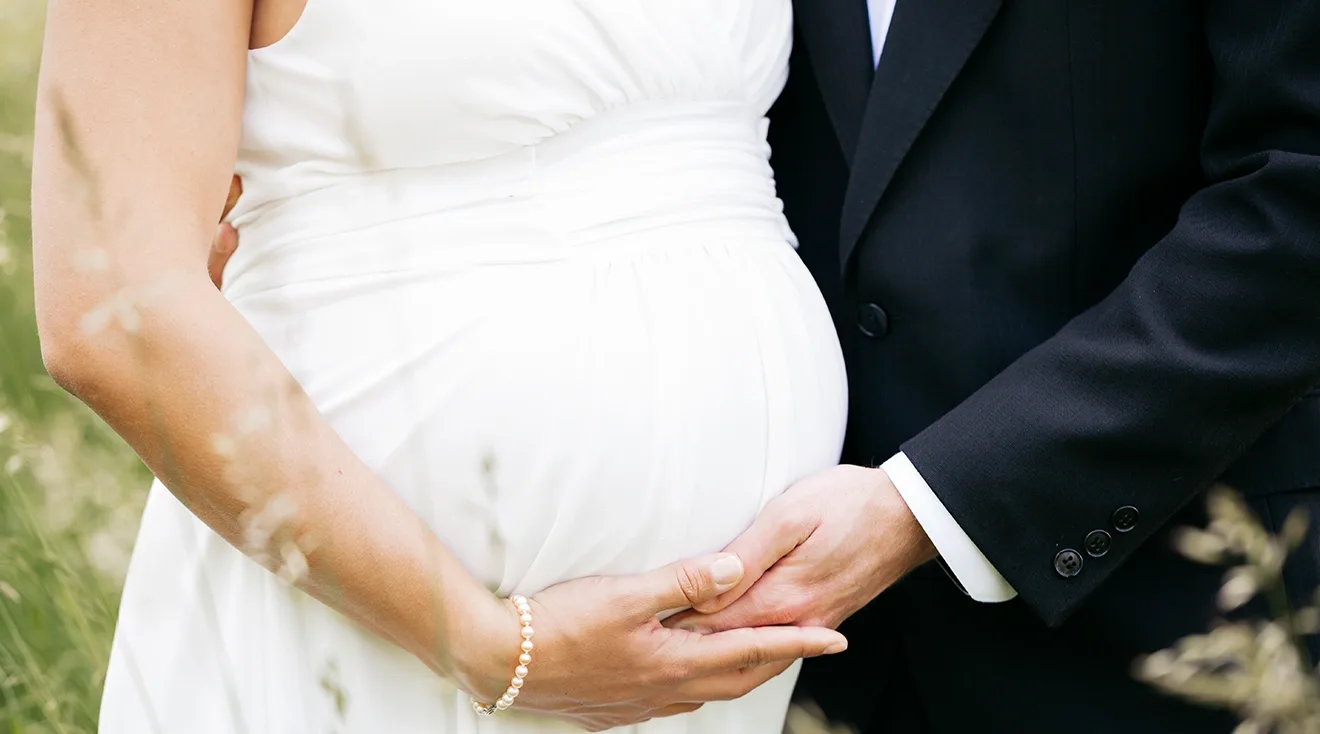 close up of pregnant bride and groom on wedding day