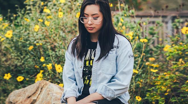 sad woman looking down and sitting outside on a rock