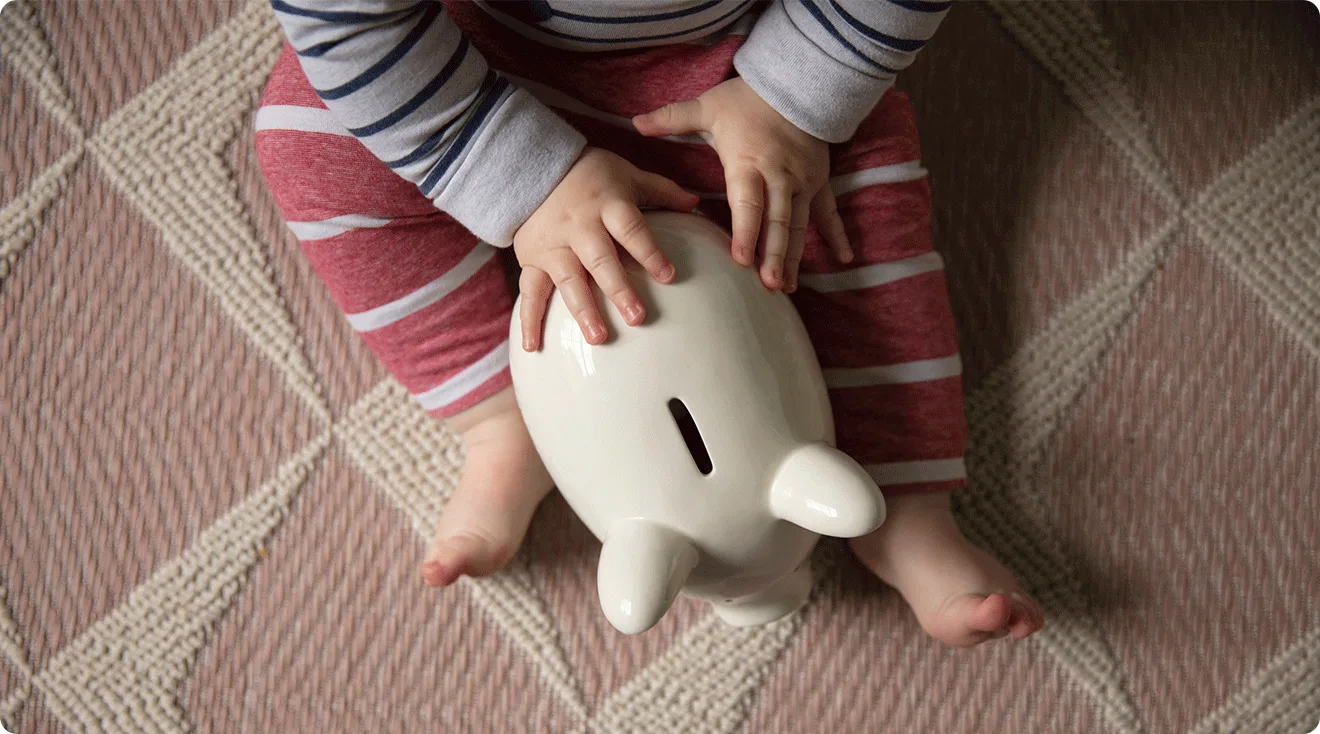 baby with piggy bank on floor